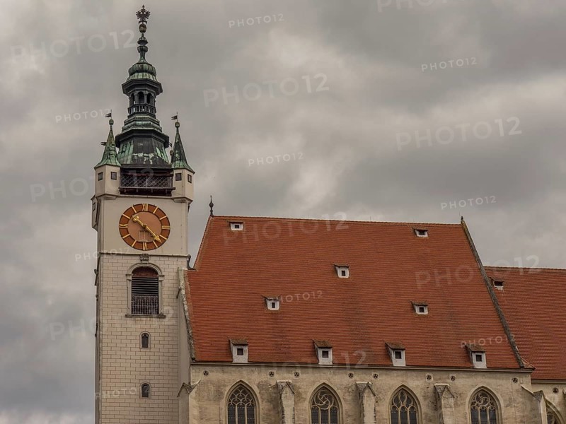Church with a red roof and a Gothic clock tower under a cloudy sky, Dürnstein, Wachau, Danube, Austria, Europe