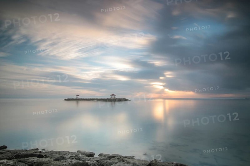 Beautiful seascape in the morning. Tropical sandy beach with breakwater and reflection of the sky in the calm water. Morning landscape, taken in Sanur, Bali, Indonesia, Asia