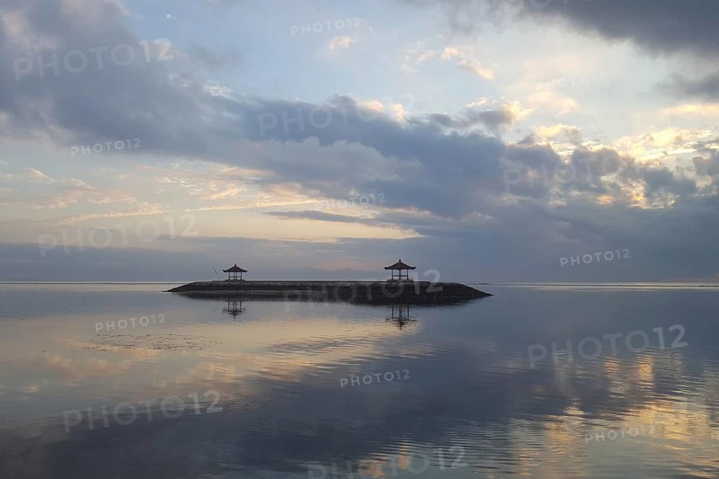 Beautiful seascape in the morning. Tropical sandy beach with breakwater and reflection of the sky in the calm water. Morning landscape, taken in Sanur, Bali, Indonesia, Asia