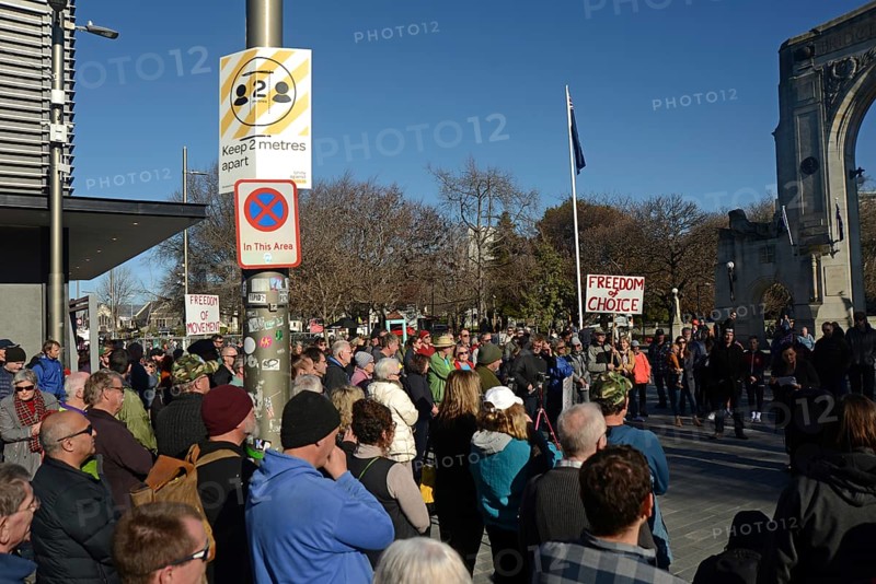 CHRISTCHURCH, NEW ZEALAND, JULY 24, 2021, The crowd ignores social distancing signage at a protest rally at the Bridge of Remembrance in Christchurch. Activists spoke against increasing government control over Covid vaccinations, farm taxes and civil liberties