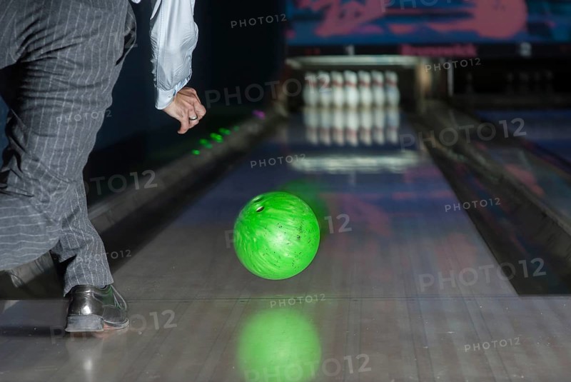 Person throwing a green bowling ball