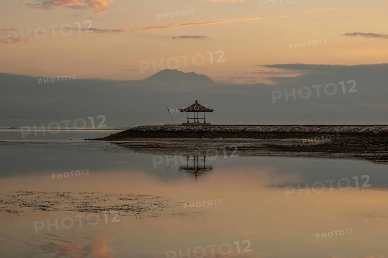Beautiful seascape in the morning. Tropical sandy beach with breakwater and reflection of the sky in the calm water. Morning landscape, taken in Sanur, Bali, Indonesia, Asia