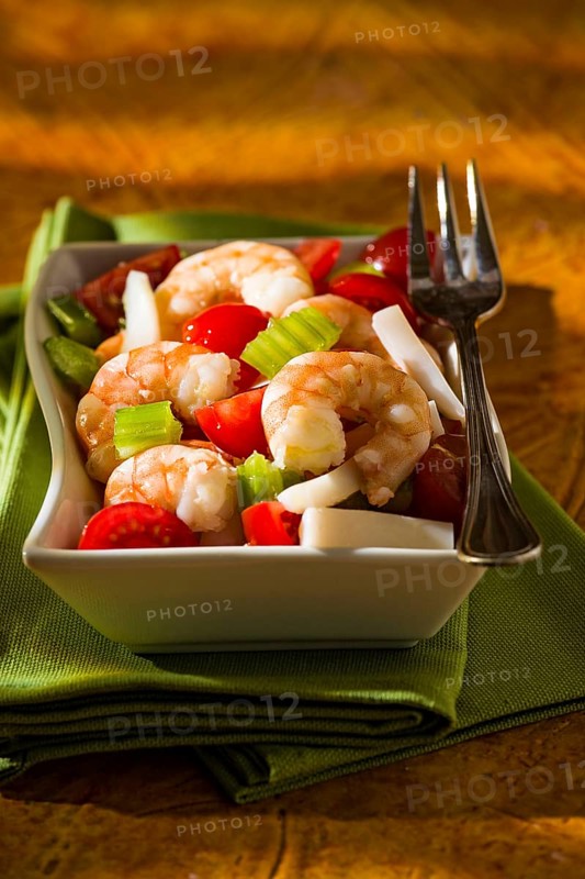 Shrimp salad with squid tomatoes celery inside a white bowl