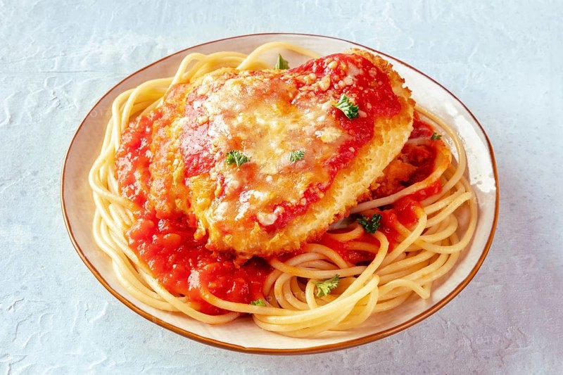 Chicken Parmesan, Italian pasta dish. Breaded chicken breast with cheese and spaghetti with tomato sauce, on a slate background, Food photography
