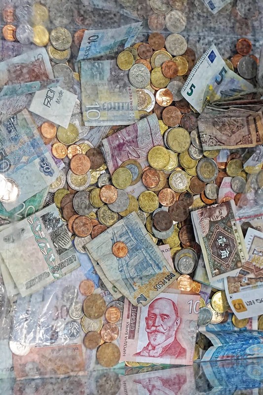 Mix coins and banknotes currency in clear donation money box