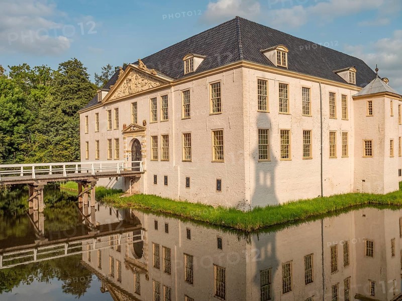 Majestic castle with white facades and blue roofs, perfectly reflected in the surrounding moat, dornum, east frisia, germany