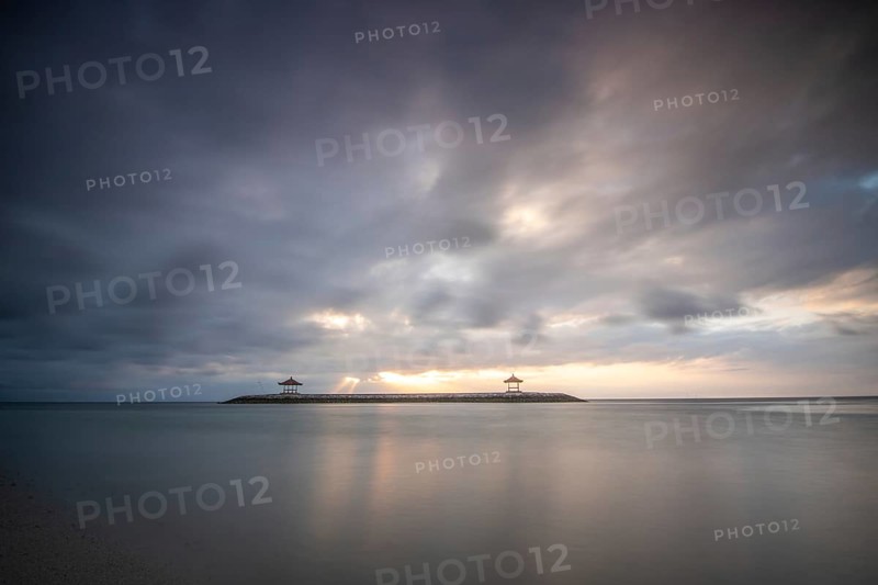 Beautiful seascape in the morning. Tropical sandy beach with breakwater and reflection of the sky in the calm water. Morning landscape, taken in Sanur, Bali, Indonesia, Asia