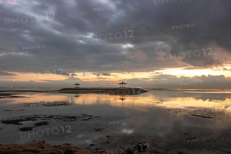 Beautiful seascape in the morning. Tropical sandy beach with breakwater and reflection of the sky in the calm water. Morning landscape, taken in Sanur, Bali, Indonesia, Asia