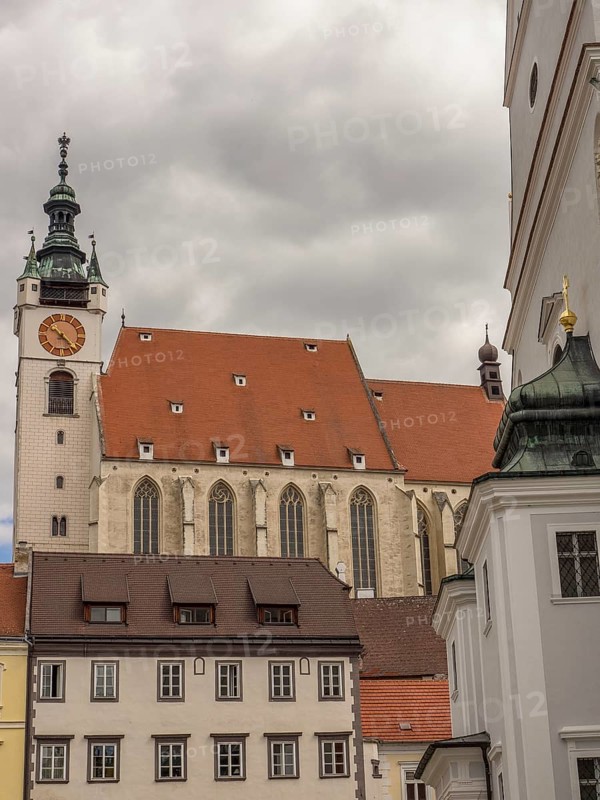 Gothic church with a striking clock tower and surrounding buildings under an overcast sky, Dürnstein, Wachau, Danube, Austria, Europe
