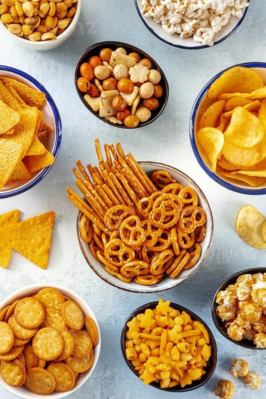 Salty snacks, party mix. A variety of crispy appetizers, shot from the top. Tortilla and potato chips, crackers, popcorn etc, Food photography