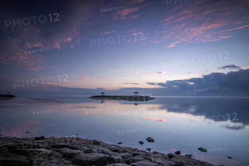Beautiful seascape in the morning. Tropical sandy beach with breakwater and reflection of the sky in the calm water. Morning landscape, taken in Sanur, Bali, Indonesia, Asia