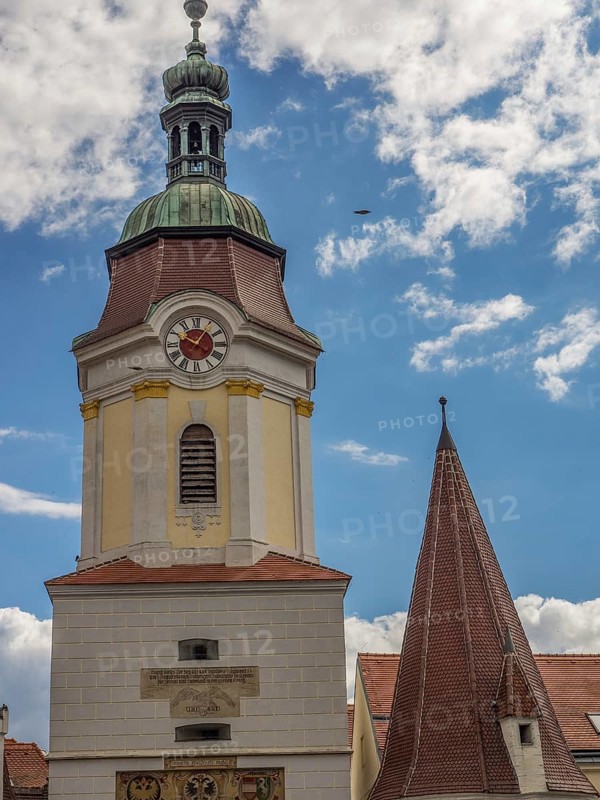 A towering clock tower and a steep church spire against a cloudy sky, Dürnstein, Wachau, Danube, Austria, Europe