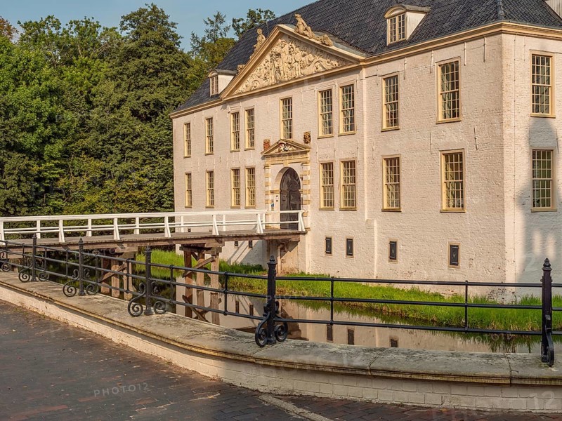 Historic white castle on the moat with decorative façade and blue roof, connected by a bridge, dornum, east frisia, germany