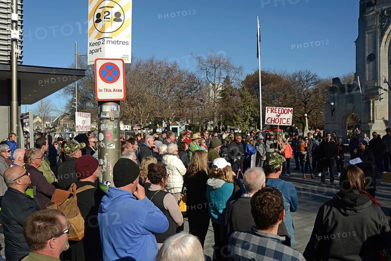 CHRISTCHURCH, NEW ZEALAND, JULY 24, 2021, The crowd ignores social distancing signage at a protest rally at the Bridge of Remembrance in Christchurch. Activists spoke against increasing government control over Covid vaccinations, farm taxes and civil liberties