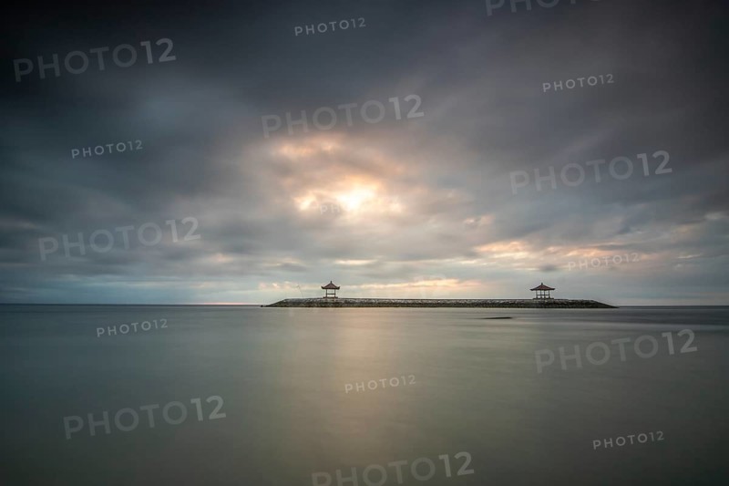 Beautiful seascape in the morning. Tropical sandy beach with breakwater and reflection of the sky in the calm water. Morning landscape, taken in Sanur, Bali, Indonesia, Asia
