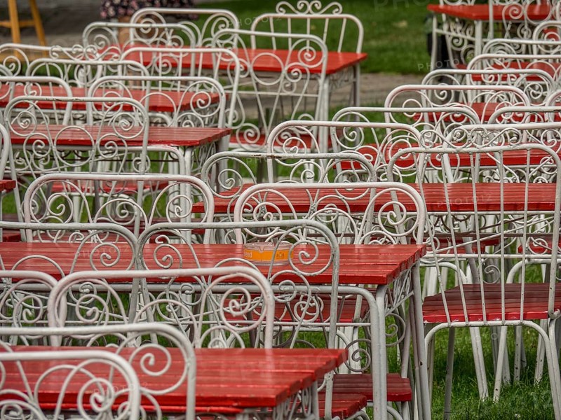 White-painted metal tables and chairs with red seats and table tops, standing in a pattern on a green lawn, ystad, sweden, baltic sea, scandinavia