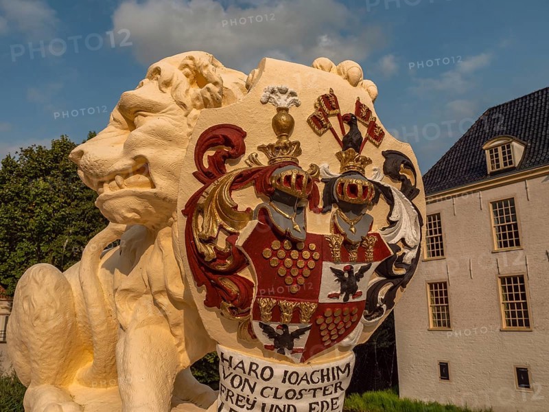 Detailed view of a lion statue with coat of arms, building in the background, dornum, east frisia, germany