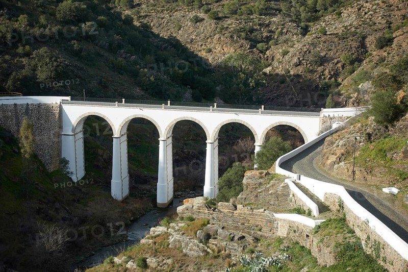 Mertola beautiful white and stone bridge on the city entrance with almond trees on the landscape in Alentejo, Portugal, Europe