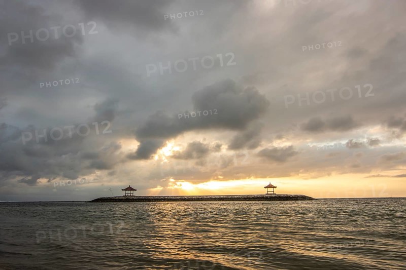 Beautiful seascape in the morning. Tropical sandy beach with breakwater and reflection of the sky in the calm water. Morning landscape, taken in Sanur, Bali, Indonesia, Asia