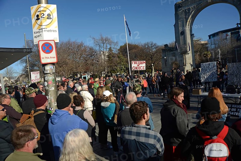 CHRISTCHURCH, NEW ZEALAND, JULY 24, 2021, The crowd ignores social distancing signage at a protest rally at the Bridge of Remembrance in Christchurch. Activists spoke against increasing government control over Covid vaccinations, farm taxes and civil liberties
