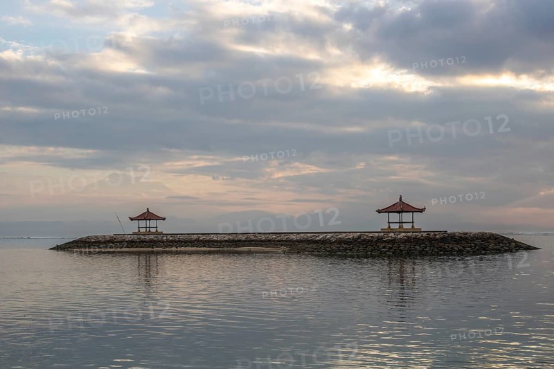 Beautiful seascape in the morning. Tropical sandy beach with breakwater and reflection of the sky in the calm water. Morning landscape, taken in Sanur, Bali, Indonesia, Asia
