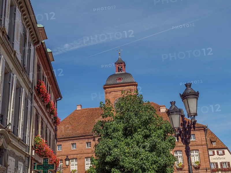 Historic building on the market square surrounded by trees and lanterns under a blue sky, Weissenburg, Alsace, France, Europe