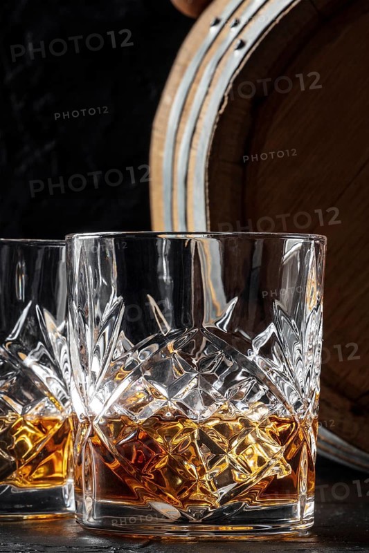 Whiskey in a glass with a barrel. Bourbon whisky and a cask on a dark background, an elegant close-up, Food photography
