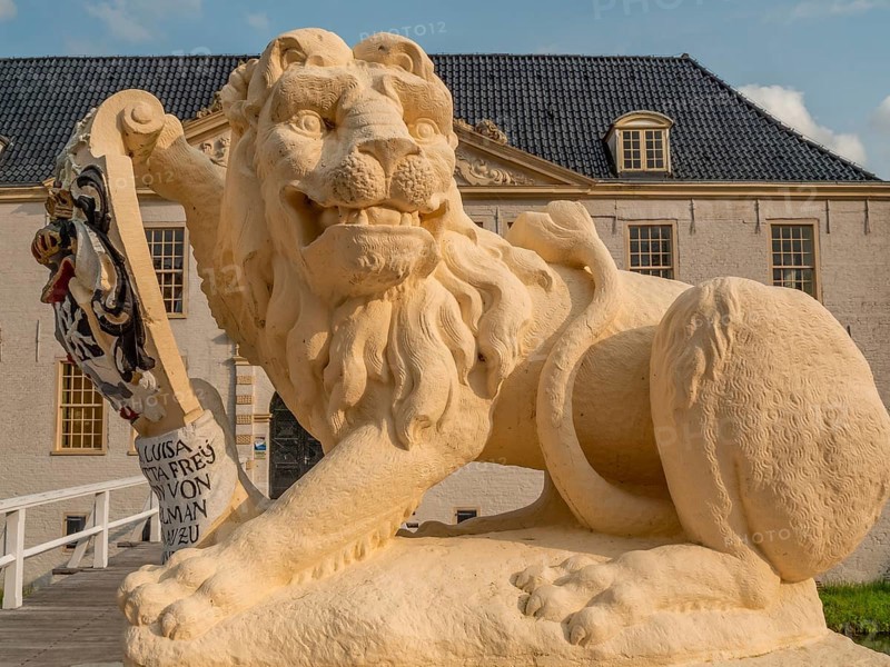 Lion statue with coat of arms in close-up in front of a historic building, dornum, east frisia, germany