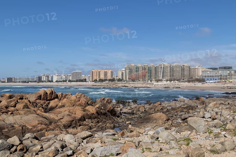 Rock in front of city view with sandy beach and surf in the Atlantic Ocean, landmark She Changes, Rotunda da Anémona, sculpture by artist Janet Echelman on the beach promenade at Praia de Matosinhos beach in Matosinhos, Norte region, Porto district, Portugal, Europe