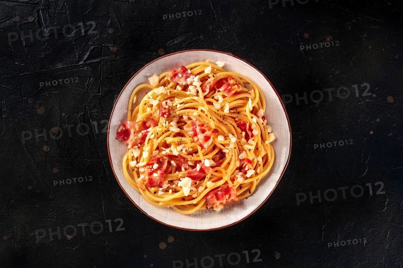 Carbonara pasta dish, traditional Italian spaghetti with pancetta and cheese, overhead flat lay shot on a black background, Food photography