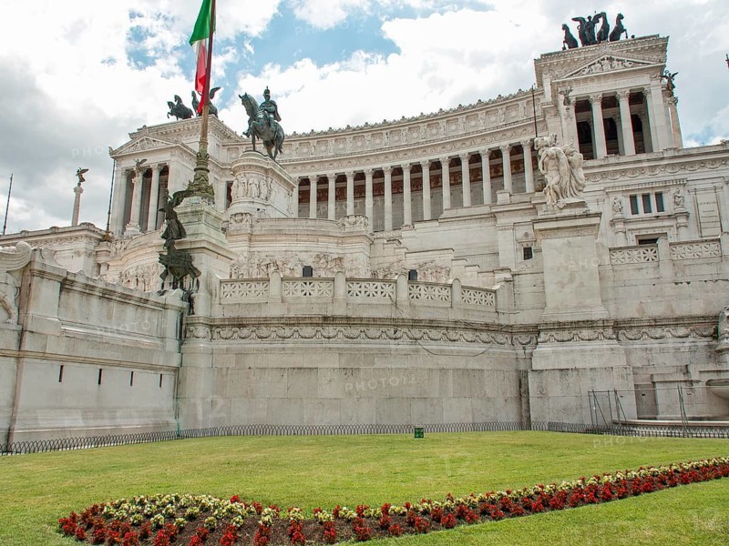 Side view of the Altar of the Nation in Rome with Italian flag and manicured lawn, rome, italy