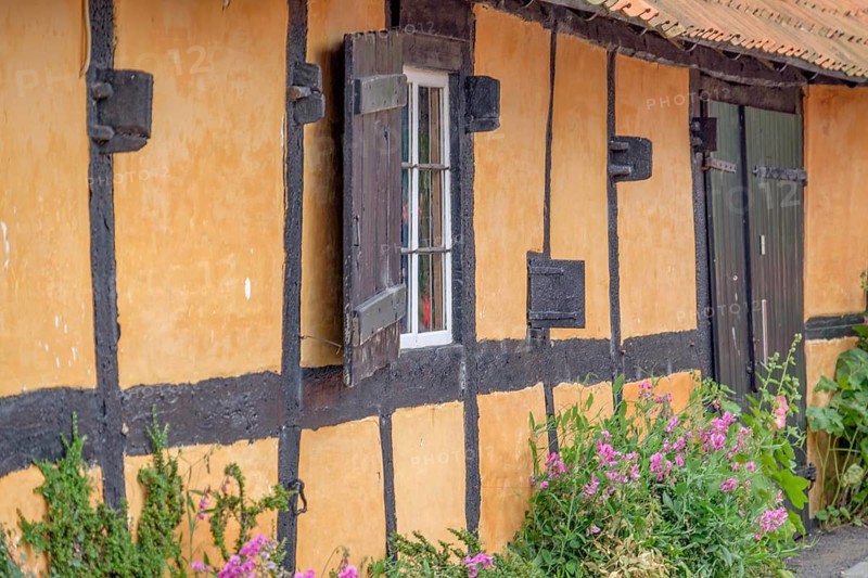 Rustic half-timbered house with colourful flowers in the foreground and striking black beams, svaneke, bornholm, baltic sea, denmark, scandinavia