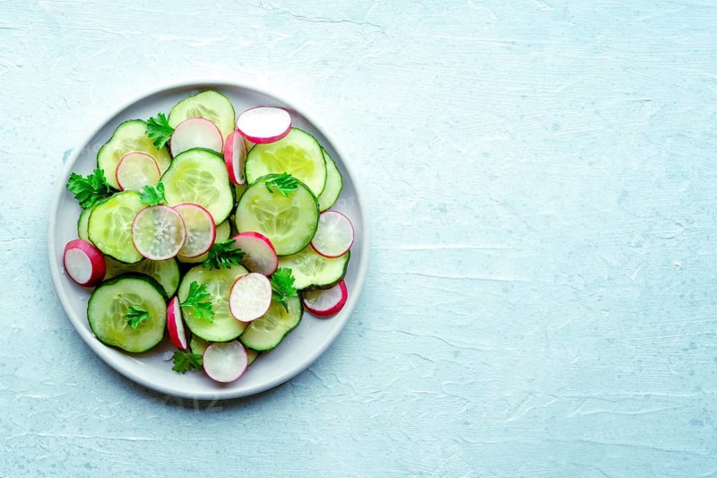 Fresh cucumber and radish salad with parsley, overhead flat lay shot. Simple vegan recipe on a slate background. Healthy diet, with a place for text, Food photography