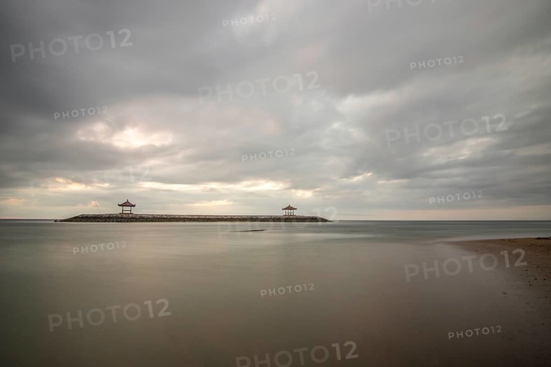 Beautiful seascape in the morning. Tropical sandy beach with breakwater and reflection of the sky in the calm water. Morning landscape, taken in Sanur, Bali, Indonesia, Asia