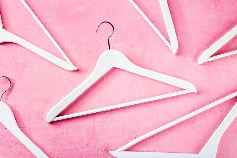 Fashion collection concept. White wooden hangers, a flat lay layout on pink. Shopping background, abstract design, Food photography