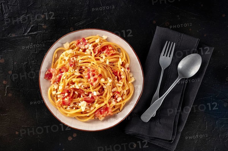 Carbonara pasta dish, traditional Italian spaghetti with pancetta and cheese, overhead flat lay shot with a fork and a spoon, on a black background, Food photography