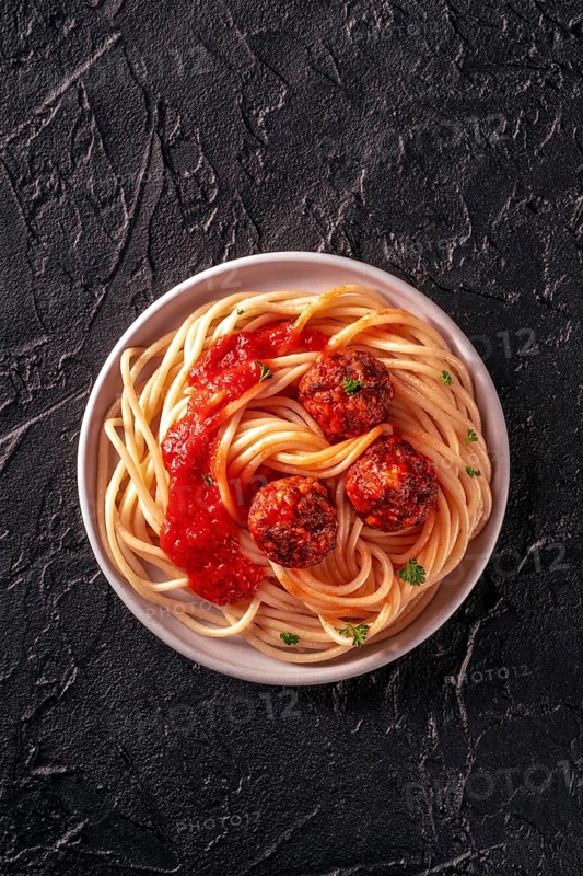 Meatballs. Beef meat balls, shot from above with spaghetti pasta, parsley, and tomato sauce, on a black background, Food photography