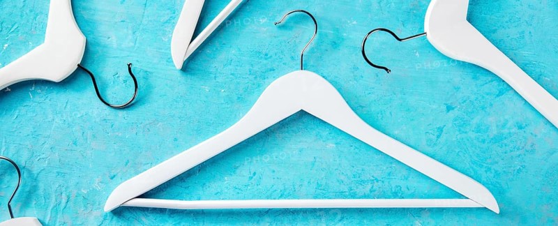 Fashion collection panorama. White wooden hangers, a flat lay layout on blue. Shopping background, abstract design