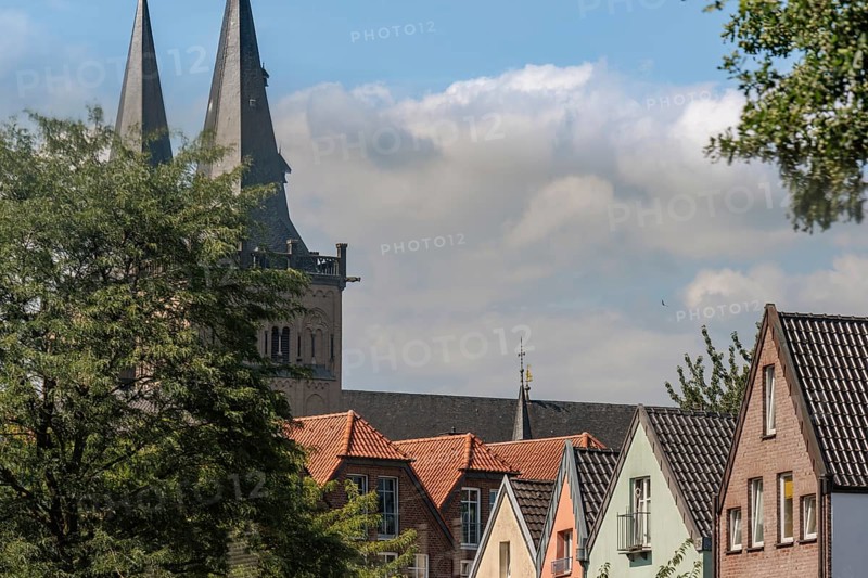 Church tower rises above colourful roof gables of houses under a cloudy sky, Xanten, Lower Rhine, North Rhine-Westphalia, Germany, Europe