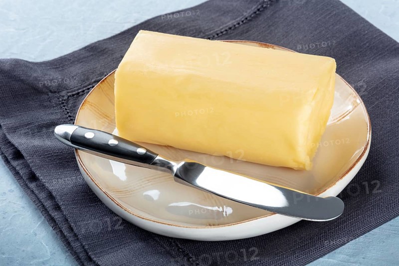 A stick of fresh butter with a knife on a plate, on a slate background, cooking ingredient, Food photography
