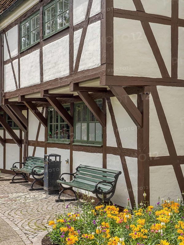 Half-timbered house with white walls and brown wooden beams, planted flower bed and green wooden benches, ystad, sweden, baltic sea, scandinavia