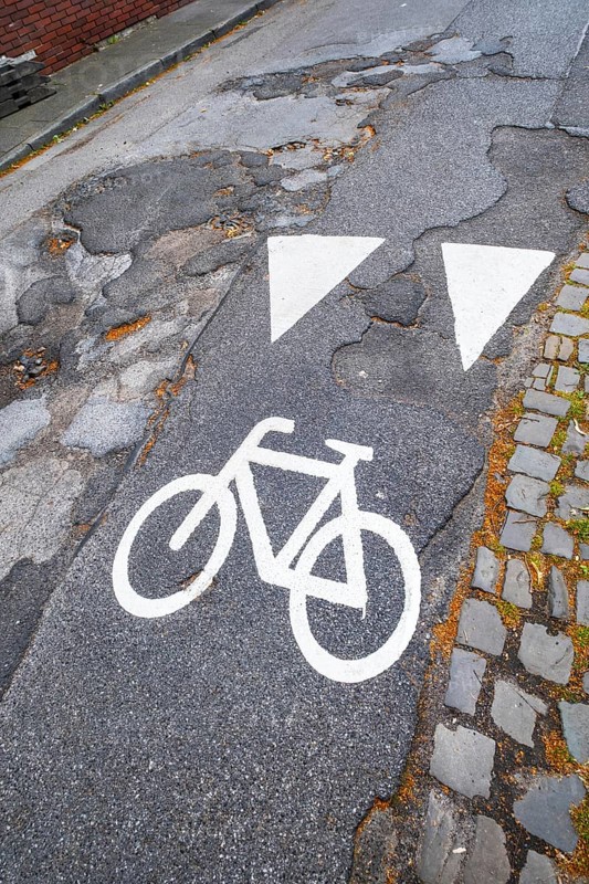 A cycle path pictogram on a road with potholes in Mönchengladbach, Germany, Europe