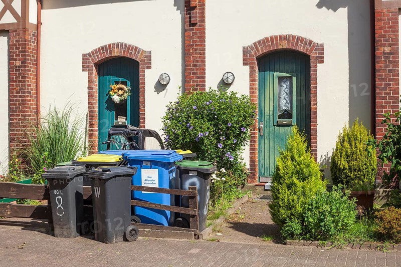 Colourful different dustbins standing in front of a house entrance, Delmenhorst, Lower Saxony, Germany, Europe