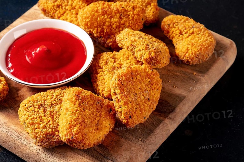 Chicken nuggets with ketchup on a wooden board, with a place for text. A crispy snack at a restaurant, a fast food dish on black, Food photography
