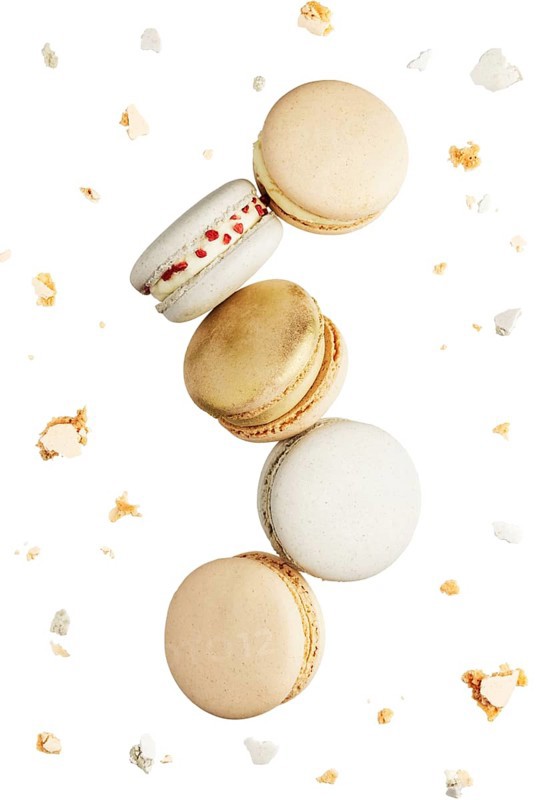 Isolated on white background white, yellow, gold macaron cookies flying, falling in motion or levitating. Colorful, sweet small French macaroon cakes. Five full cookies isolate. Broken cuts around