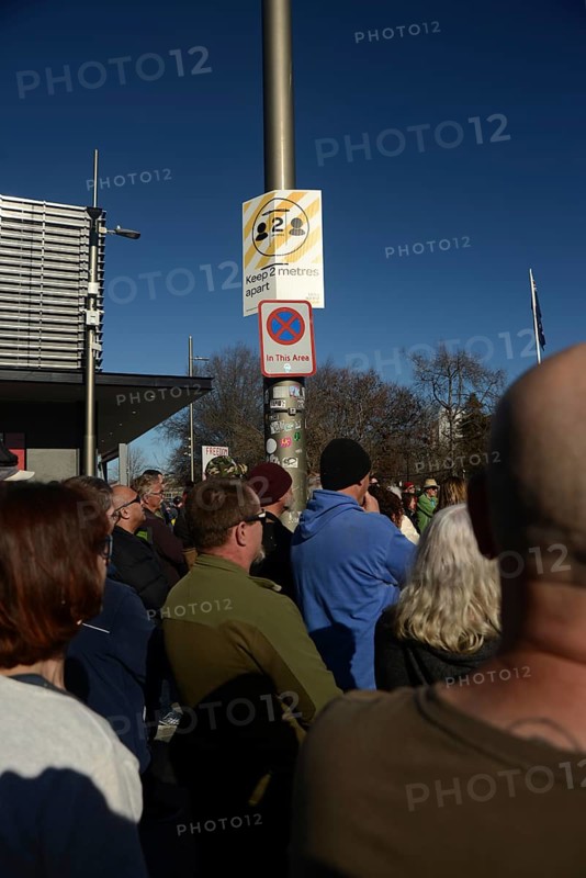 CHRISTCHURCH, NEW ZEALAND, JULY 24, 2021, The crowd ignores social distancing signage at a protest rally at the Bridge of Remembrance in Christchurch. Activists spoke against increasing government control over Covid vaccinations, farm taxes and civil liberties
