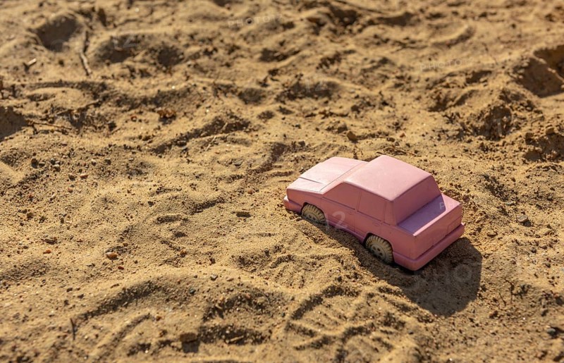 Pink toy car in the sand at a playground