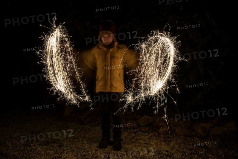 A child paints circles of light with sparklers