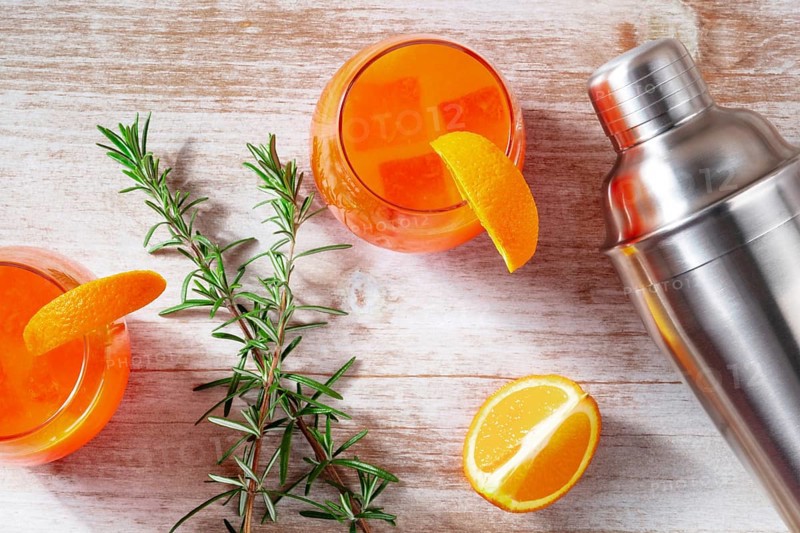 Orange cocktails with rosemary and a shaker, shot from the top on a wooden background, Food photography