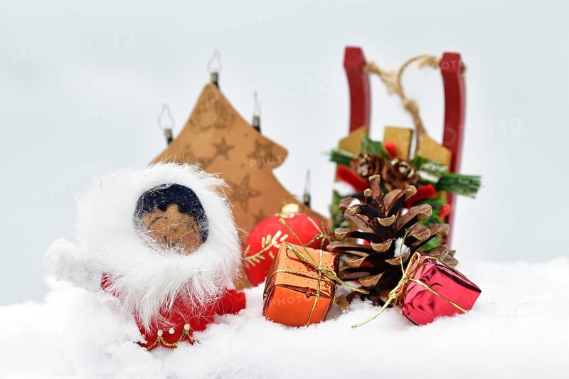 Christmas decoration, Inuit with sleigh and Christmas tree ball and pine cones and Christmas presents lying in the snow